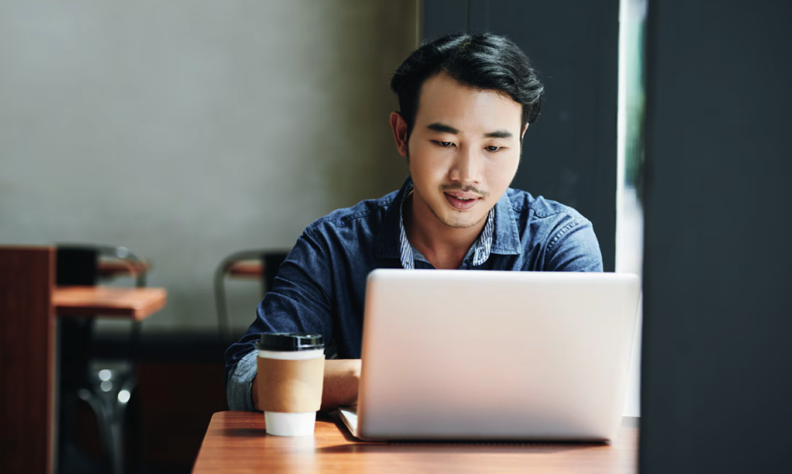 Shopline merchant focused on his laptop in a coffee shop, working on his store